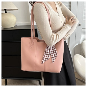 Pink leather tote bag with a checkered silk scarf handle in a modern interior setting