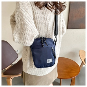 Detail of navy blue nylon crossbody bag featuring HELLO WEEKEND label and adjustable strap