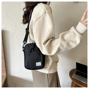 Detail view of the compact black nylon crossbody bag with adjustable shoulder strap