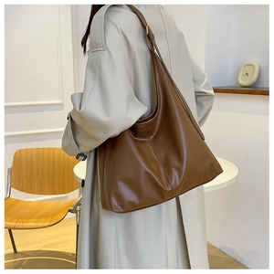 Detailed side view of the large brown leather tote bag worn as a shoulder bag