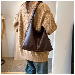 Détail d'un grand sac hobo marron foncé avec bandoulière réglable porté par un mannequin