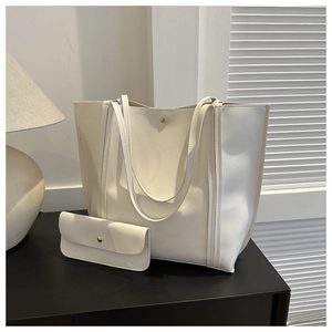 Detail view of the white PU leather tote bag with a matching envelope pouch on a black surface