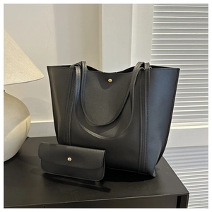 Detail of black large tote bag and matching envelope clutch with gold magnetic hardware