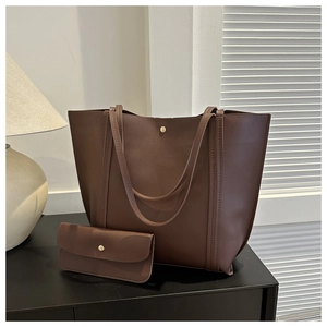 Detail view of brown leather tote bag set with a small clutch and gold metal buckle