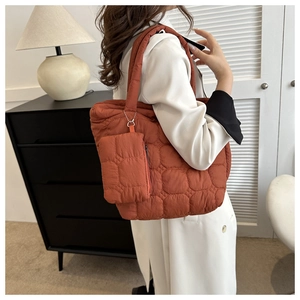 Detail of rust orange quilted tote bag with matching zipper pouch on shoulder