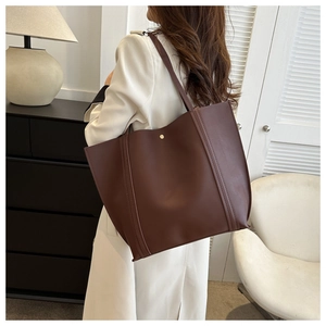 Detail of dark brown matte leather tote bag showing magnetic closure and shoulder straps