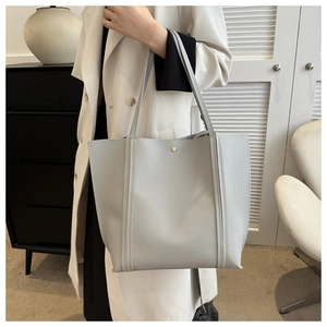 Detail of light grey PU leather tote bag with slim handles and minimalist gold rivets