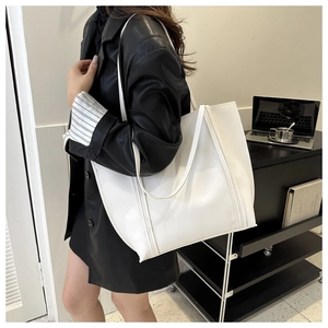 Close-up of a white leather tote bag styled with professional office attire