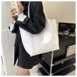 Detail of white leather tote bag showing reinforced stitching and minimalist square design