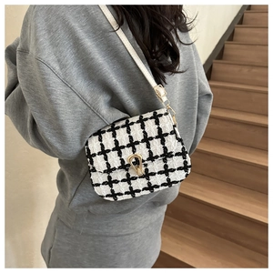 Detail showing classic black and white tweed crossbody bag with gold buckle hardware