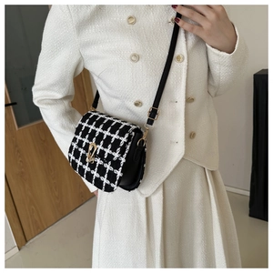 Close-up of black and white plaid tweed crossbody bag with golden rotating metal lock