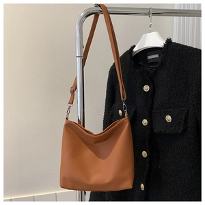 Close-up of caramel bucket bag with litchi grain texture and silver metal hardware