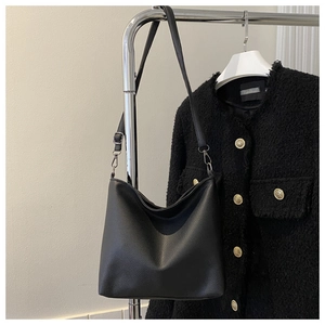 Detail of black pebbled leather bucket bag with adjustable strap and silver metal hooks