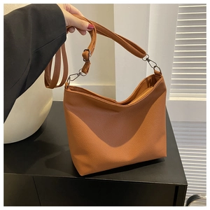 Detail of a brown lychee pattern leather bucket bag with adjustable shoulder strap and silver hooks