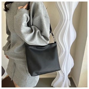 Close-up of black lychee texture leather shoulder bag with silver hardware on a model