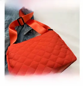 Close-up of orange quilted nylon crossbody bag featuring diamond stitching and wide strap