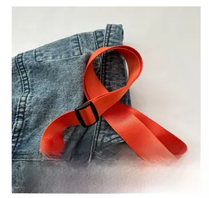 Close-up of bright orange nylon strap with black plastic buckle on a quilted bag