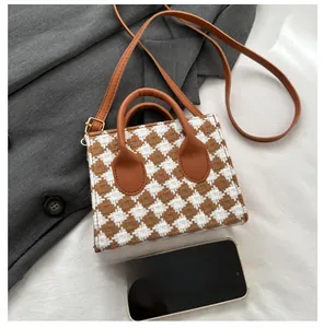 Top view of woven plaid mini square bag with leather straps and phone for size reference