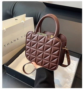 Detail of coffee brown quilted PU leather handbag with gold metal hardware and top handle