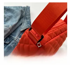 Detailed view of bright red quilted nylon crossbody bag with wide shoulder strap