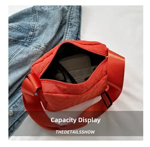 Detail view of red quilted crossbody bag with zip closure and spacious interior capacity