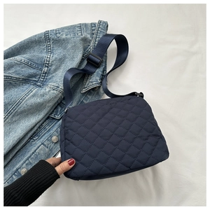 Detail of navy blue quilted crossbody bag with adjustable wide fabric strap