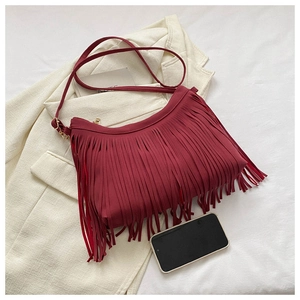 Detail of red tassel shoulder bucket bag on white blazer with phone for size reference