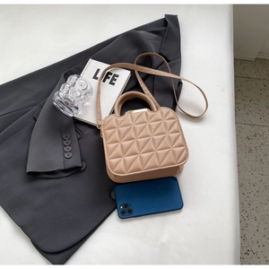 Detail view of beige quilted handbag with gold clasp, triangle stitching and size reference