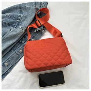 Close-up of orange quilted crossbody bag with stylish diamond pattern and wide strap