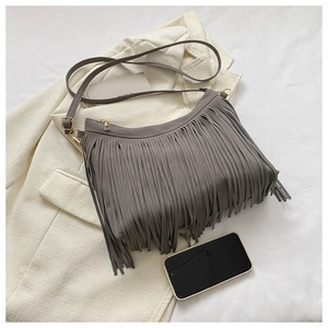 Macro shot of grey fringe bucket bag featuring smooth suede texture and gold zipper