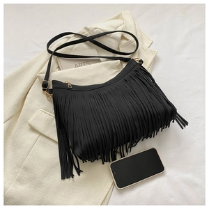 Close-up of black fringe bucket bag detail with golden metal accents on white fabric