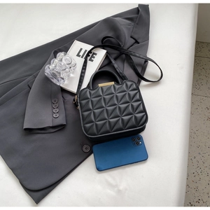 Quilted black crossbody bag shown next to a smartphone for clear size comparison