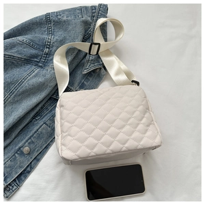 Detail view of beige quilted crossbody bag showing rhombus stitching and nylon strap