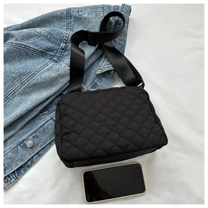 Quilted black crossbody bag detail showing classic rhombic stitching and phone for scale