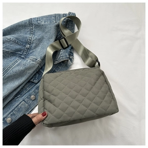 Close-up of gray quilted crossbody bag featuring a classic diamond pattern and wide strap