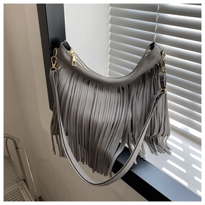 Close-up of grey tassel bucket bag featuring golden zippers and textured fringe details