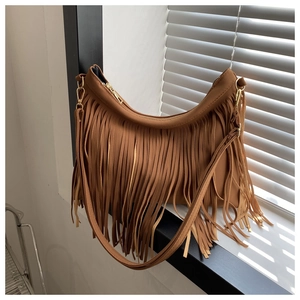 Detail shot of brown faux suede fringe handbag with bohemian tassels in natural sunlight