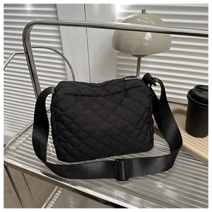 Detail of black quilted oxford cloth crossbody bag with adjustable wide strap and zipper