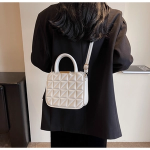 Detail of white quilted crossbody bag with golden metal hardware and top handle