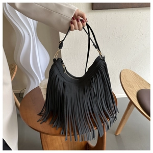 Detail of black bohemian tassel shoulder bag featuring long suede fringe and golden hardware