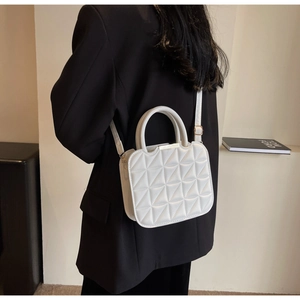 Detail view of white quilted leather bag with circular handle and gold-tone metal trim