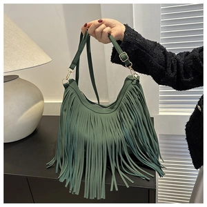 Close-up of bohemian forest green suede tassel bucket bag with gold metal buckle
