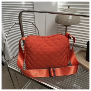 Detail of orange quilted nylon crossbody bag featuring an adjustable wide shoulder strap