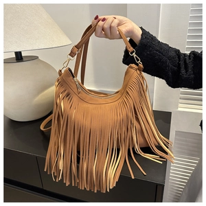Detail of brown suede bucket bag featuring long fringe tassels and golden hardware accents