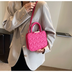Close-up of rose red quilted crossbody bag with geometric texture on a light suit