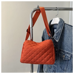 Detail of orange quilted shoulder bag with rhombus stitching and adjustable strap