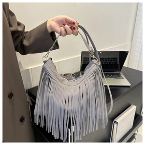 Detail of grey suede hobo bag with long fringes, golden hardware and shoulder strap