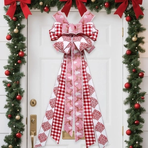 Große Weihnachtsbaumschleife mit Rentier-Motiv auf weißer Tür mit festlichem Kranz