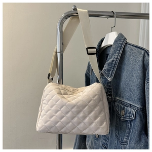 Close-up of off-white quilted shoulder bag with diamond pattern and adjustable strap
