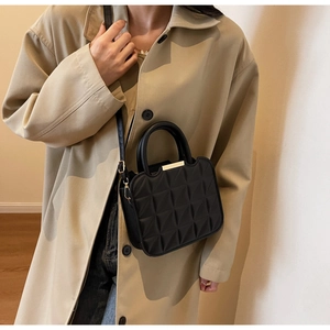 Detail of 3D quilted faux leather bag with gold metal trim and round top handles
